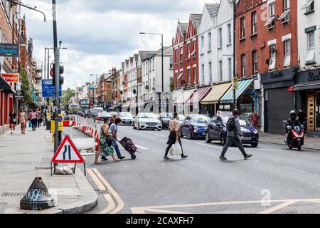 Fußgänger überqueren die Straße in Green Lanes, Harringay, einem normalerweise blühenden und geschäftigen Einkaufsviertel, während der Coronavirus-Pandemie, North London, Großbritannien Stockfoto