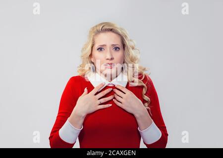 Junge blonde Frau im roten Kleid, Hände auf die Brust im tiefen Schock und Verwunderung an Kamera suchen Stockfoto