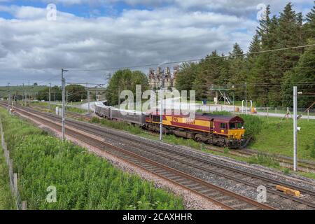 DB Cargo-Lokomotive der Baureihe 66, die einen Güterzug mit Kalkablagerungen von Tata Hardendale auf der Westküsten-Hauptstrecke bei Shapfell abtransportiert Stockfoto