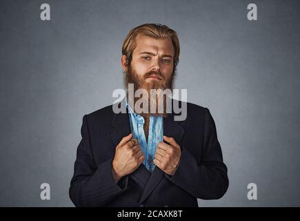 Zuversichtlich bärtigen hipster Geschäftsmann stand gerade an Sie mit seinen Armen, schwarzen Anzug Jacke isoliert auf Grau Grau studio Wand Hinterg Stockfoto