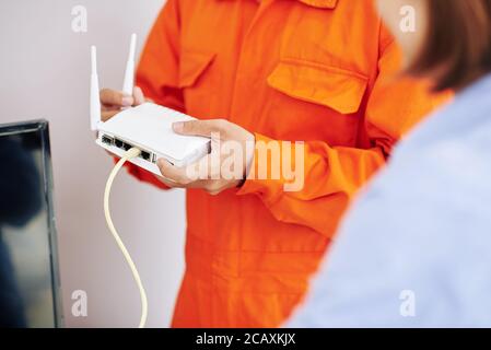 Nahaufnahme des Elektrikers, der Frau erklärt, wie man Wi-Fi benutzt Router, den er gerade installiert hat Stockfoto