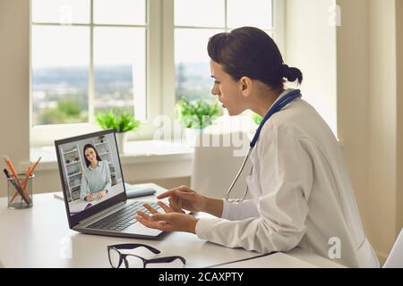 Eine junge Ärztin in ihrer Klinik gibt eine Online-Konsultation mit einem Laptop. Stockfoto