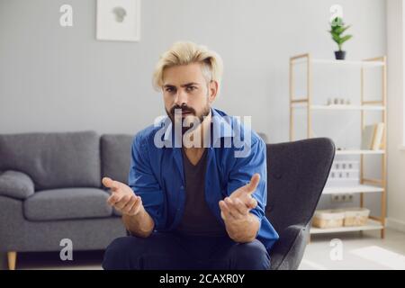 Verwirrt Hipster Mann sitzt im Sessel zu Hause Stockfoto