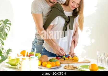 Junger Mann und Frau schneiden Zutaten sehr sorgfältig. Zugeschnittenes Foto Stockfoto