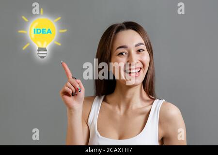 Konzept der Ideen- und Informationssuche. Porträt einer jungen kaukasischen Frau, die glücklich eine neue Idee entdeckt. Grauer Hintergrund. Speicherplatz kopieren. Stockfoto