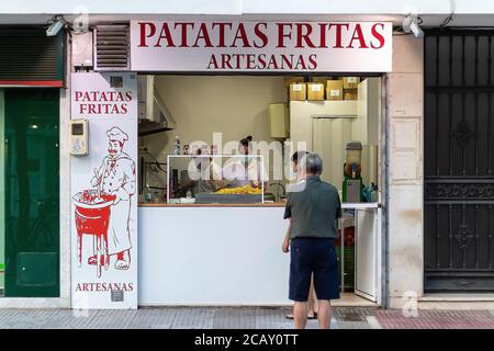 Punta Umbria, Huelva, Spanien - 7. August 2020: Verkäufer in einem lokalen verkauft Kartoffelchips. Gebratene Kartoffeln sind typische lokale Straßengerichte. Sie trägt Protective Stockfoto