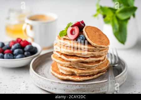 Gesunde Haferpfannkuchen mit Beeren auf einem handwerklichen Keramikplatte. Veganes Frühstück Stockfoto