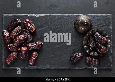 Getrocknete Datteln auf schwarzem Schiefergrund. Draufsicht mit Platz für Text. Islamisch-arabisches Essen Stockfoto