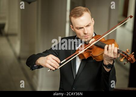 Junge kaukasische talentierte wunderschönen Mann un tux spielen Geige, professionelle Musiker Praxis Leistung, verwenden klassische Instrument. Musikkonzept Stockfoto