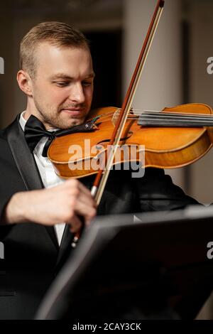 Junge kaukasische gut aussehende Kerl spielen Geige, talentierte Musiker führen Musik mit dem Einsatz von klassischen Instrument, trägt elegante formale Anzug, vor Co Stockfoto