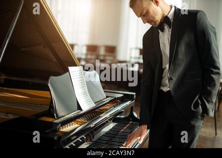 Talentierter junger kaukasischer Pianist Mann üben, führen tolle Musik. Musiker in formell eleganten Anzug Klavier spielen Stockfoto