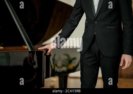 Porträt eines jungen kaukasischen Mannes in formell eleganten Anzug neben Klavier, professionelle Musiker nach der Aufführung Stockfoto