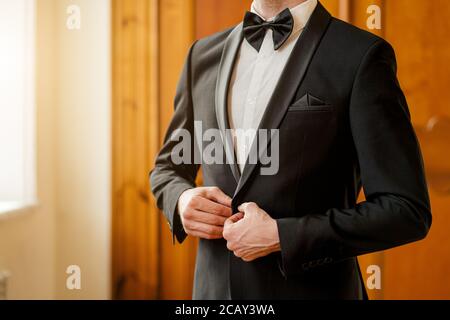 3/4-Mann im formellen Anzug mit Schleife Bindegürtel Knöpfe in der Jacke. Männlich in eleganten stilvollen Anzug drinnen Stockfoto