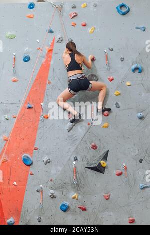 Junge flexible Frau klettern an der Wand in der Turnhalle, Rückansicht voller Länge Foto. Hobby, Lifestyle, Freizeit Stockfoto