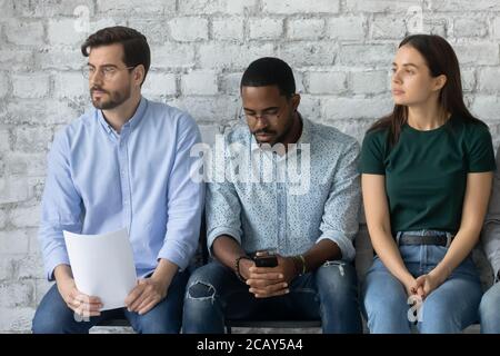 Müde verschiedene Kandidaten warten auf Vorstellungsgespräch, sitzen in der Warteschlange Stockfoto