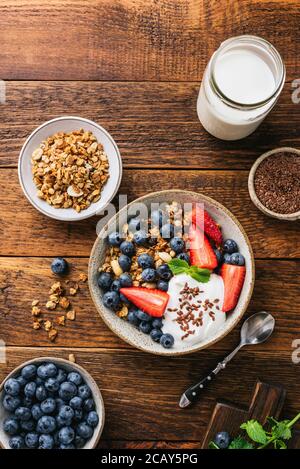 Müslischale mit Heidelbeeren, Erdbeeren und griechischem Joghurt auf rustikalem Holztisch-Hintergrund. Draufsicht Stockfoto