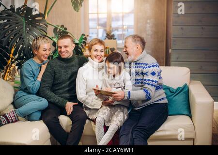 Nette, angenehme Familie, die Erinnerungen teilt, während sie auf der weißen Couch sitzt. Stockfoto