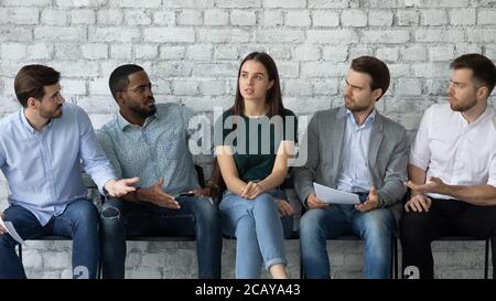Aggressive verschiedene Männer, die auf selbstbewusste Frau, sitzen in der Schlange Stockfoto