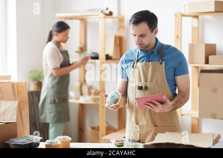 Waist up Porträt von reifen Arbeiter trägt Schürze Verpackungsaufträge, während Sie am Holztisch stehen, Lebensmittel-Lieferservice, Kopierer Platz Stockfoto