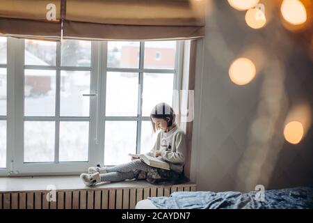 Nettes kleines Mädchen mit einem Buch. Seitenansicht Foto. Angenehme liebenswert Mädchen ist auf das Lesen ihres Lieblingsbuches konzentriert Stockfoto