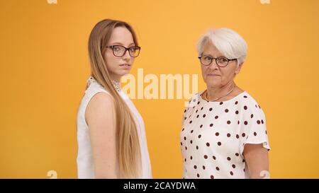 Junge und ältere Frau stehen vor einander und blicken auf die Kamera. Isoliert. Hochwertige Fotos Stockfoto