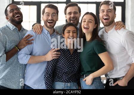 Überglücklich lachend verschiedene Mitarbeiter, die gemeinsam auf die Kamera schauen Stockfoto