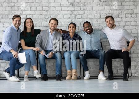 Portrait lächelnd verschiedene Kandidaten Geschäftsleute umarmen, sitzen in Reihe Stockfoto