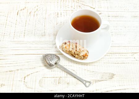 Tasse Tee und eine Bar Müsli. Weißer Holzhintergrund Stockfoto