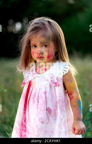 Das kleine Mädchen war mit holi-Farbe bedeckt. Ein Mädchen in einer grünen Lichtung. Haare auf Stockfoto
