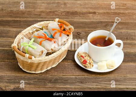 Korb mit Riegel, eine Tasse schwarzen Tee und eine Bar Müsli Stockfoto