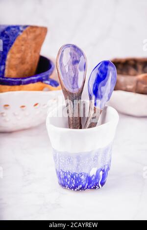 Keramik auf weißem Marmor Hintergrund gesetzt. Weiße, blaue und braune Farben. Tassen, Löffel, Schüsseln. Handgefertigt Stockfoto