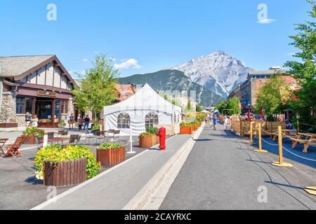 BANFF, KANADA - 29. JULI 2020: Touristen wandern entlang der Banff Avenue im Banff National Park mit Cascade Mountain im Hintergrund. Die Straße war geschlossen Stockfoto