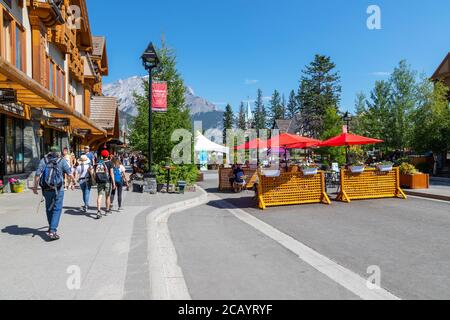 BANFF, KANADA - 29. JULI 2020: Touristen gehen und essen entlang der Banff Avenue im Banff National Park. Die Straße wurde wegen COVID-19 geschlossen, um Mo zu ermöglichen Stockfoto