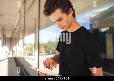 Schöner kaukasischer Mann mit digitalen Tablet, während an der Hochschule stehen campus Stockfoto