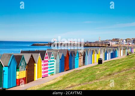 Bunte Strandhütten und Herne Bay Pier in Herne Bay, Kent, Großbritannien Stockfoto