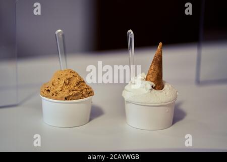 Zwei Becher italienisches Gelato mit Plastiklöffeln auf einem weißen Tisch von Livanti, Alicante, Spanien Stockfoto