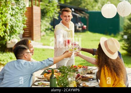 Porträt eines lächelnden jungen Mannes Toasting mit Freunden beim Abendessen auf der Terrasse im Sommer, kopieren Raum Stockfoto