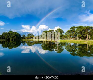 Sarasota, USA, 8. August 2020. Ein Regenbogen und Bäume spiegeln sich in einem Teich in den Meadows, Sarasota, Florida. Kredit: Enrique Shore/Alamy Stock Foto Stockfoto