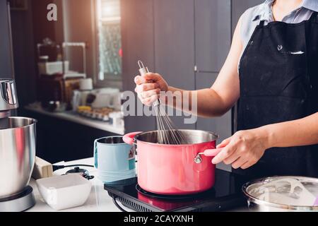 Schöne Frau Kochen Schneebesen Teig in Schüssel manuell von Hand Bei hausgemachten Stockfoto