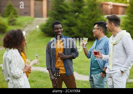 Multi-ethnische Gruppe von Menschen trinken Cocktails und plaudern, während draußen Party im Sommer genießen, kopieren Raum Stockfoto