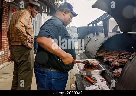 Ein Mann grillt im Regen vor dem Red's Blues Club während des Sunflower Blues and Gospel Festival, 13. August 2016, in Clarksdale, Mississippi. Stockfoto