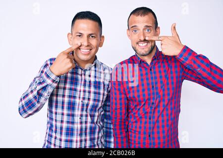 Junge Homosexuell Paar von zwei Männern tragen lässige Kleidung zeigt mit der Hand Finger auf Gesicht und Nase, lächelnd fröhlich. Beauty-Konzept Stockfoto
