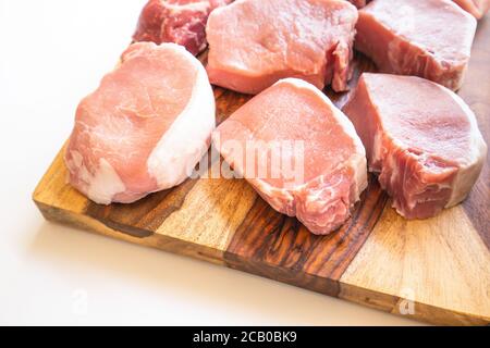 Knochenlose rohe Schweinelende Koteletts aus nächster Nähe auf Holzschneidebrett Stockfoto