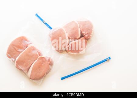 Reißverschlussbeutel mit knochenlosen Schweinelende Koteletts, Nahaufnahme, weißer Hintergrund, direkt von oben Stockfoto