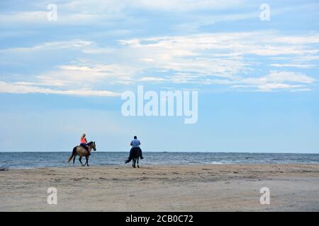 Ein Pärchen reiten am Strand entlang der Cape Hatteras National Seashore an den Outer Banks von North Carolina. Stockfoto