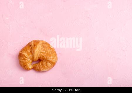 Draufsicht ein Croissant auf dem rosa Hintergrund und Textur. Stockfoto