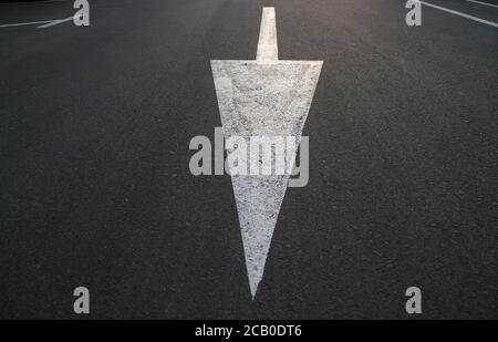 Langer weißer Pfeil nach unten auf schwarzem Hintergrund, abgewinkelte Perspektive. Stockfoto