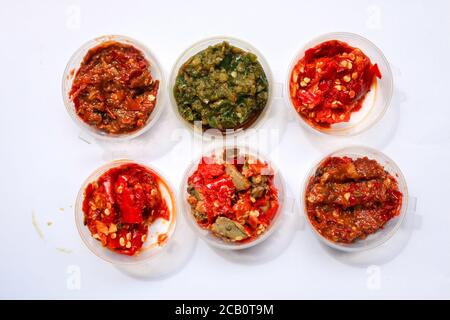 Aneka Sambal Indonesia. Fünf Arten von indonesischen würzigen Würze in Untertassen von Mini-Schüssel überzogen. In der Nähe befindet sich ein Korb mit frischen Chilischoten. Stockfoto