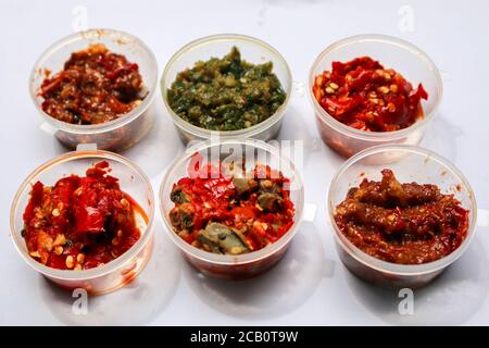 Aneka Sambal Indonesia. Fünf Arten von indonesischen würzigen Würze in Untertassen von Mini-Schüssel überzogen. In der Nähe befindet sich ein Korb mit frischen Chilischoten. Stockfoto