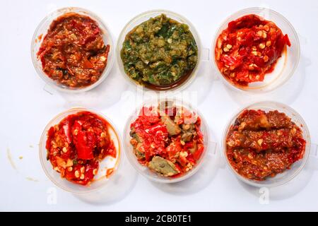 Aneka Sambal Indonesia. Fünf Arten von indonesischen würzigen Würze in Untertassen von Mini-Schüssel überzogen. In der Nähe befindet sich ein Korb mit frischen Chilischoten. Stockfoto